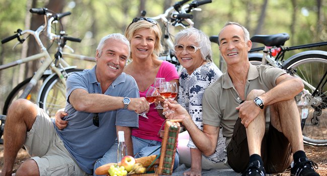 Two older couples enjoying a picnic in the woods