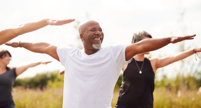 Group Of Mature Men And Women In Class At Outdoor Yoga Retreat