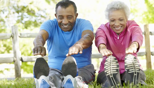 Senior African American Couple Exercising In Park Stretching To Touch Toes